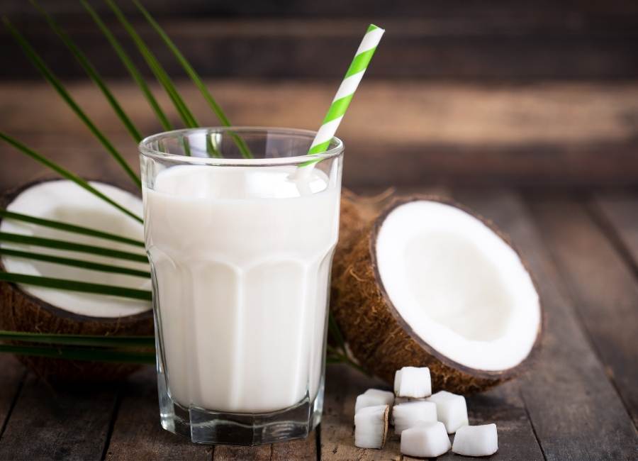 coconut milk in a glass with straw and coconuts