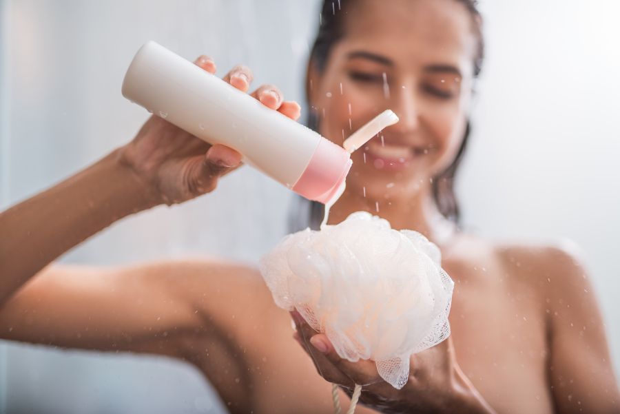 woman taking out the shampoo on a loofah during a shower