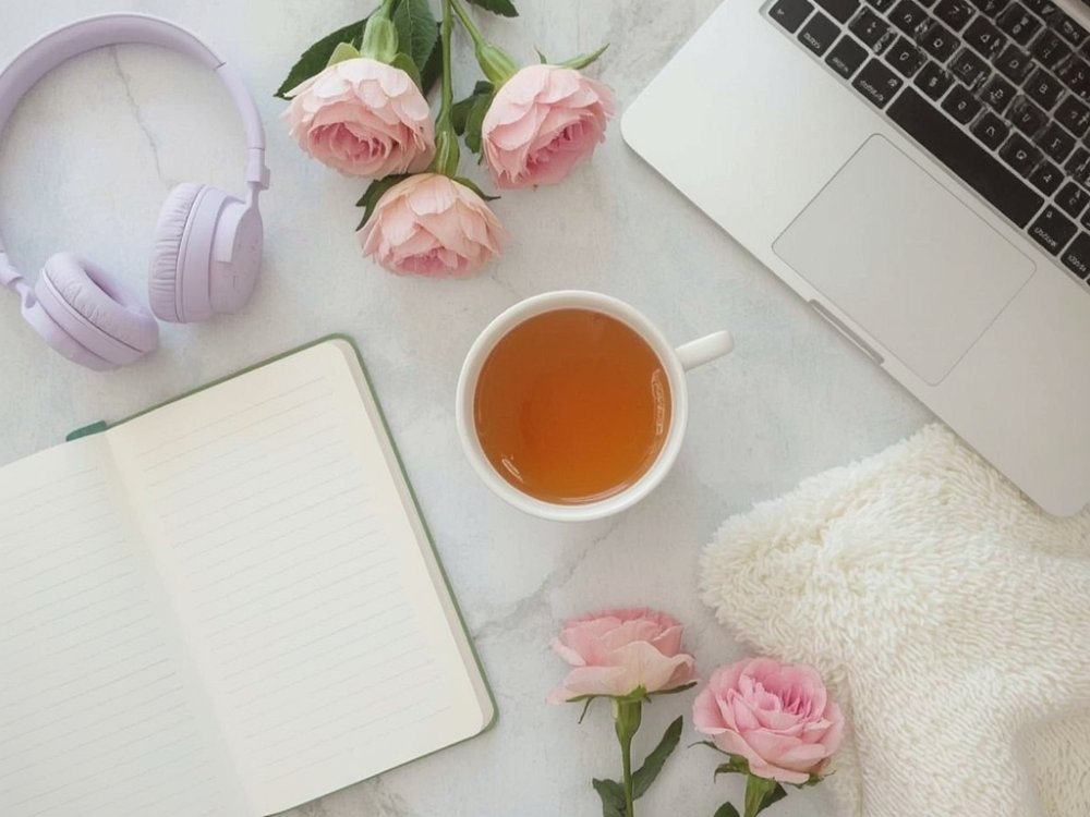 Quick 5-Minute Pick-Me-Up Ideas : Collage-style flat lay with journal, cup of tea, headphones, blooming flowers, and open laptop on a cozy desk, bright airy background, symbolizing balance of mind, body, and heart.